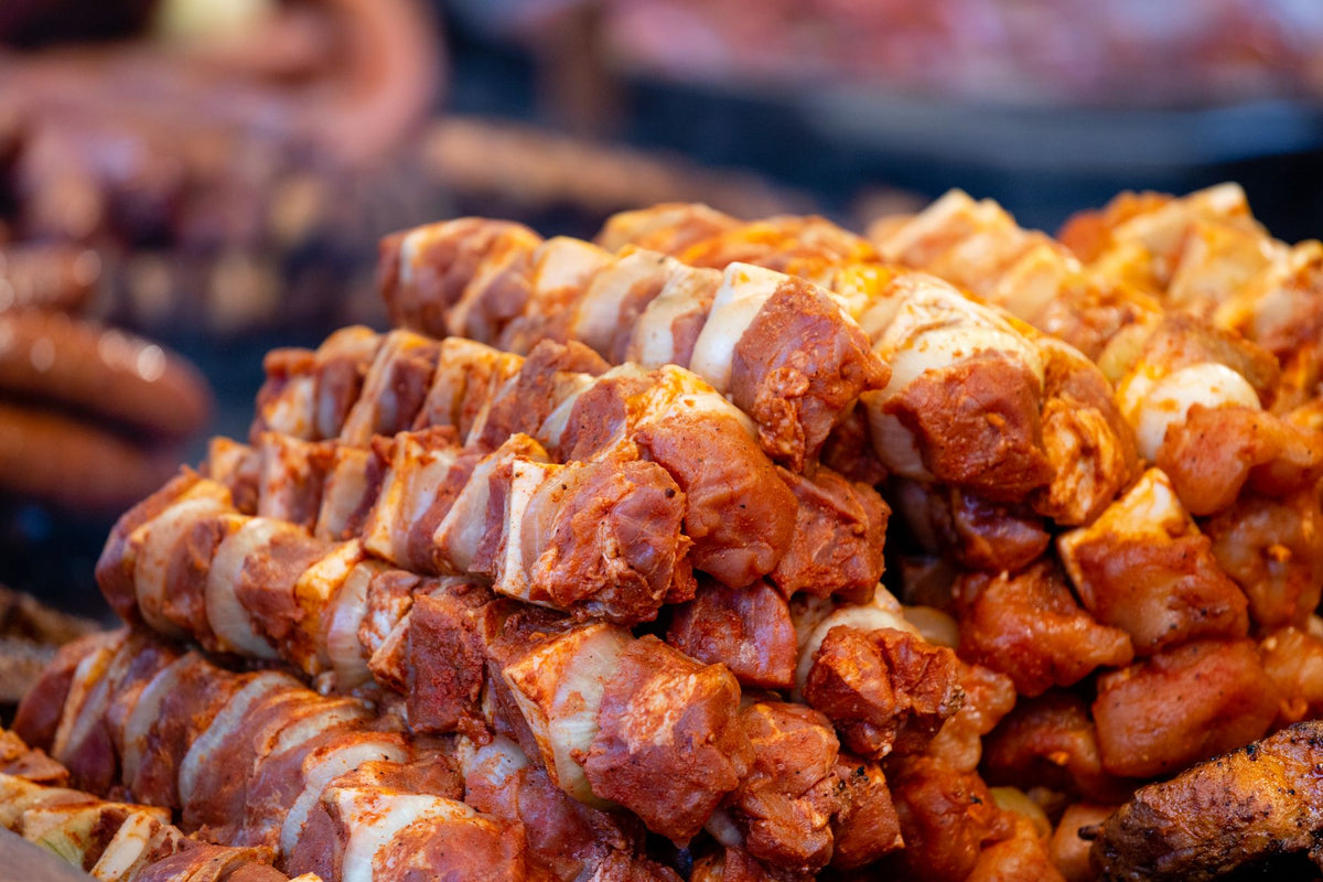 Juicy marinated pork skewers piled on a barbecue, ready for grilling.