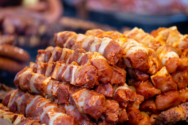 Juicy marinated pork skewers piled on a barbecue, ready for grilling.