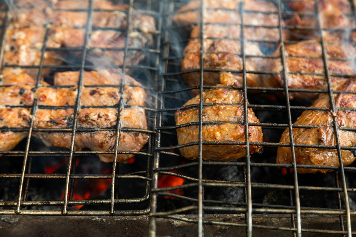 Close-up of succulent meat grilling on a charcoal barbecue, producing delicious smoky flavors.