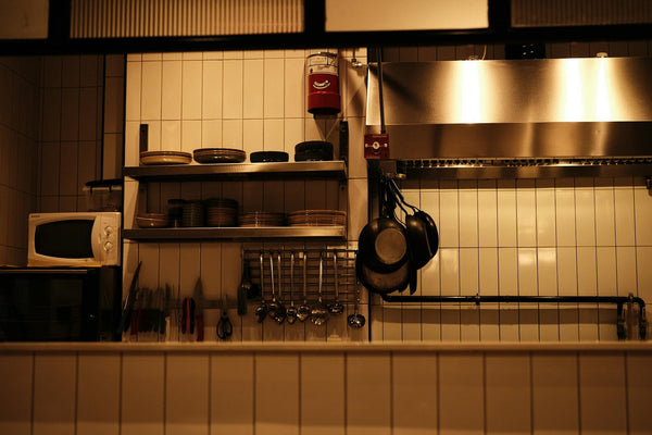 A well-organized restaurant kitchen with utensils, pans, and a microwave oven.