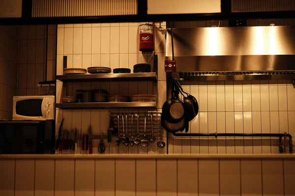 A well-organized restaurant kitchen with utensils, pans, and a microwave oven.