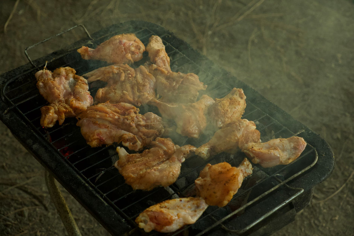 Juicy chicken wings sizzling on a charcoal grill, perfect for outdoor barbecues.