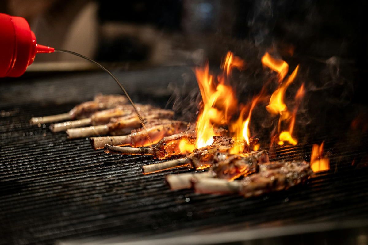 Close-up of meat grilling over an open flame, highlighting culinary techniques in Vancouver.