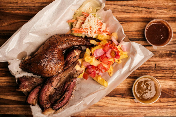 Mouthwatering barbecue platter with smoked meats, coleslaw, and cheesy fries served on a rustic wooden table.