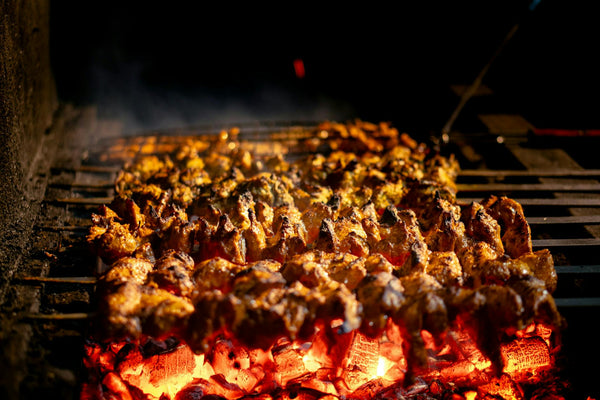 Delicious chicken skewers roasting on open grill with glowing coals and smoky flavor