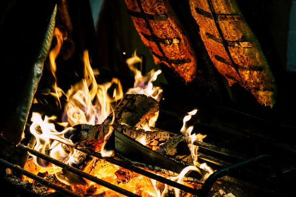 Close-up of grilled fish cooked over an open flame, highlighting fire and heat.
