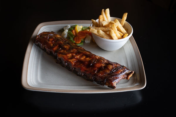 Delicious BBQ spare ribs served with french fries and mixed vegetables on a plate.